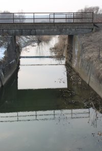 This bridge has high, vertical concrete sides to the channel under the bridge, extending some way either side.  Click for larger version