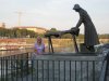 A statue of a lady washing the carpets at the river of Ticino, next to the roofed bridge